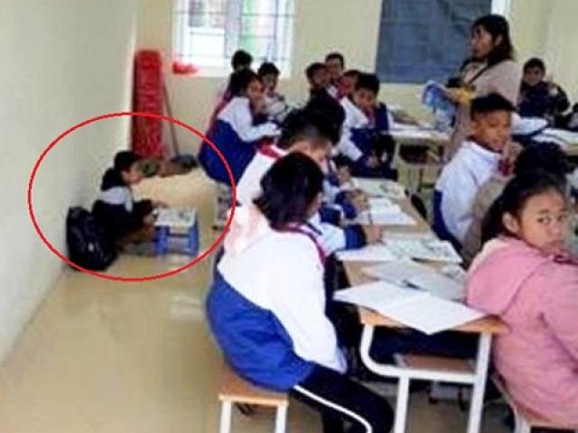 Một học sinh bị cô giáo phạt ngồi dưới sàn học bài vì quên khăn quàng đỏ