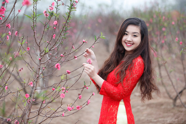 Nữ sinh diện áo dài đỏ khoe sắc bên những khóm hoa đào
