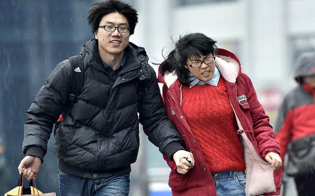 Một cặp đôi nắm tay nhau chạy trong cơn mưa tới nhà ga Thiên Tân, phía bắc Trung Quốc ngày 15.2.  Người ngoại tỉnh làm ăn xa nhà ở Trung Quốc bắt đầu "mùa về quê" thường niên, thường từ tháng 2 và kết thúc vào tháng 3.