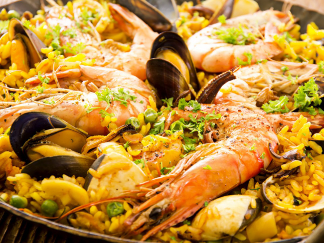 Thưởng thức một chảo bự paella - cơm nghệ hải sản và xúc xích tại Can Majó, nhà hàng bên bờ biển nổi tiếng của Barcelona, Tây Ban Nha.