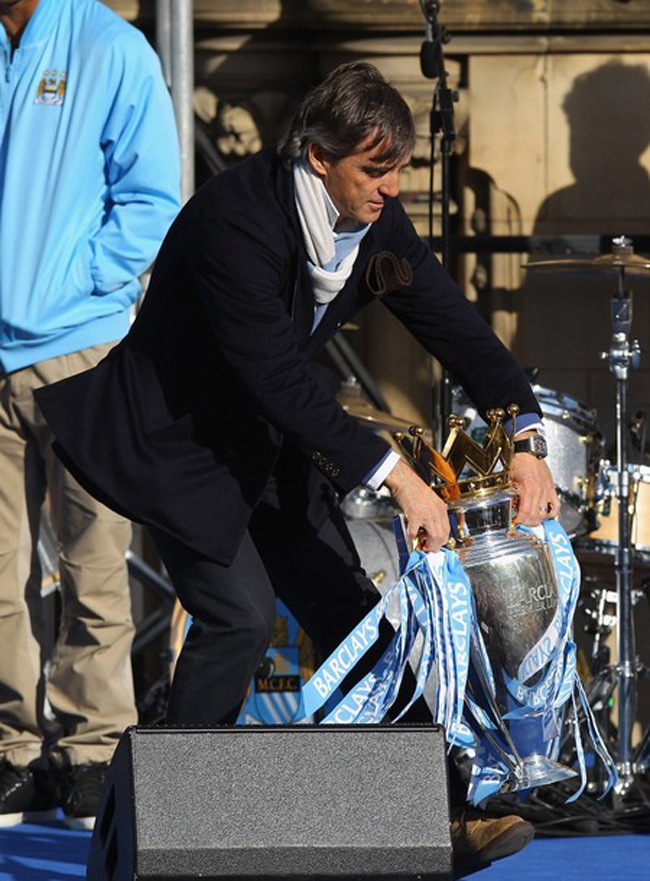 HLV Roberto Mancini cẩn thận cầm chiếc cúp mà ông đã lao tâm khổ tứ cùng các học trò đoạt được.