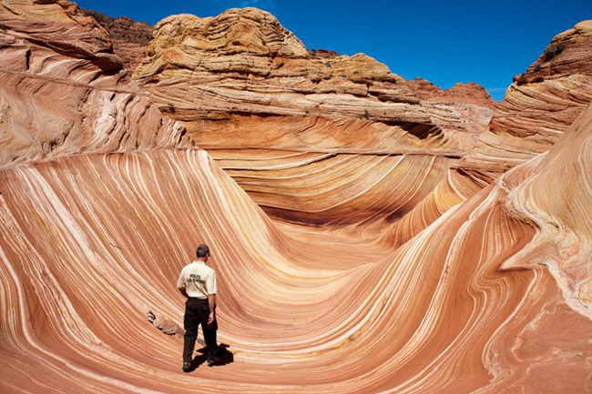 Núi đá The Wave (làn sóng) nằm giữa hai bang Arizona và Utah (Mỹ), gồm những lòng chảo hình chữ U đã bị xói mòn.&nbsp;Chính những trận mưa to hay cơn gió mạnh đã làm xói mòn vùng núi đá, tạo thành những vùng lõm và cũng làm nên những “họa tiết” uốn lượn, quanh co tuyệt đẹp của nơi đây.
