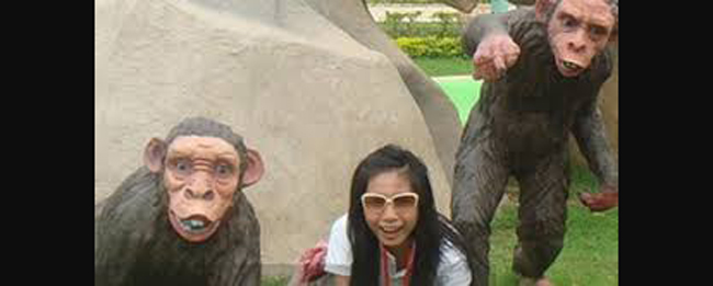 Ảnh quá khứ Thủy Tiên chụp tại một khu công viên giải trí. Cô bắt chước tạo dáng giống như tượng của một chú khỉ trên bãi cỏ.
