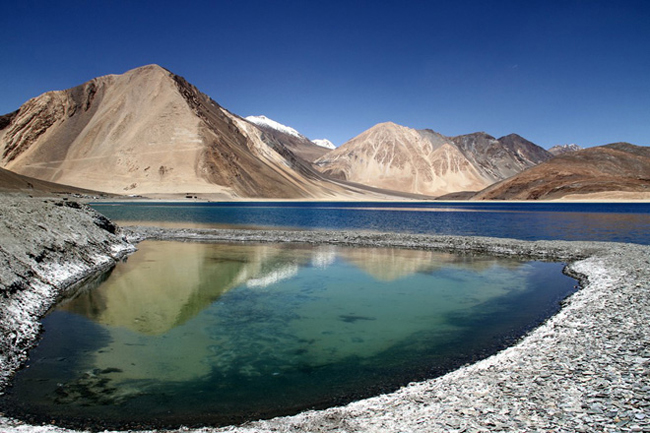 Pangong Tso theo tiếng Tây Tạng là “hồ hẹp, dài, mê hoặc”. Mặt hồ như tấm kính phản chiếu những ngọn núi khô cằn phía sau nó.


