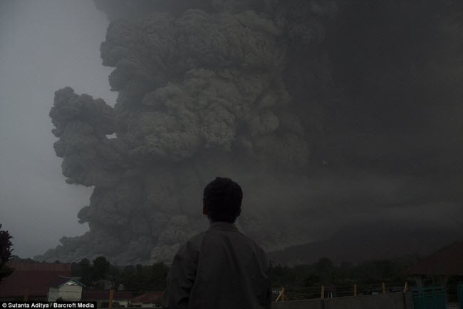 Một người dân địa phương đứng nhìn núi lửa Sinabung phun trào cột tro bụi khổng lồ lên bầu trời.