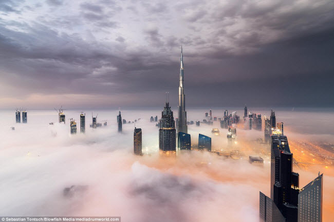 Nhiếp ảnh gia Sebastian Tontsch, 27 tuổi, đã lên đỉnh một tòa tháp cao 90 tầng tại Dubai để ghi lại cảnh tượng những tòa nhà chọc trời nhấp nhô trong màn sương sớm tại thành phố này.