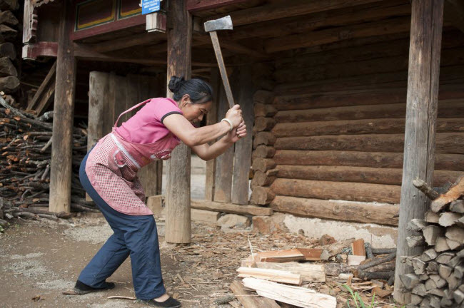 Người phụ nữ của bộ tộc Mosuo vẫn phải làm phần lớn công việc nặng nhọc trong gia đình như bổ củi.