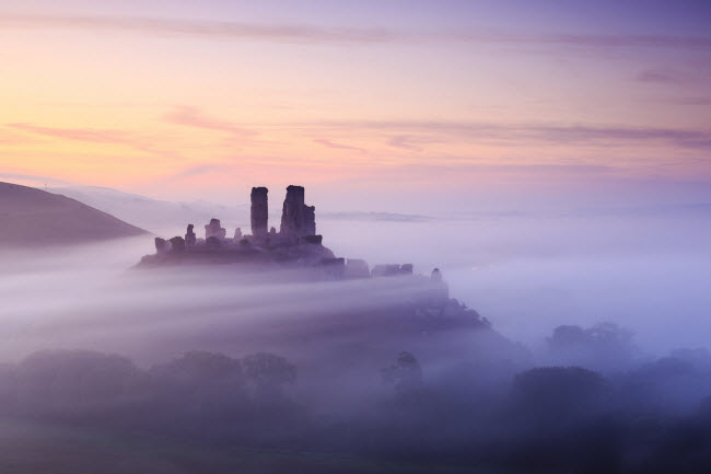 Sương mù bao quanh lâu đài Corfe lúc bình minh Dorset, Anh.