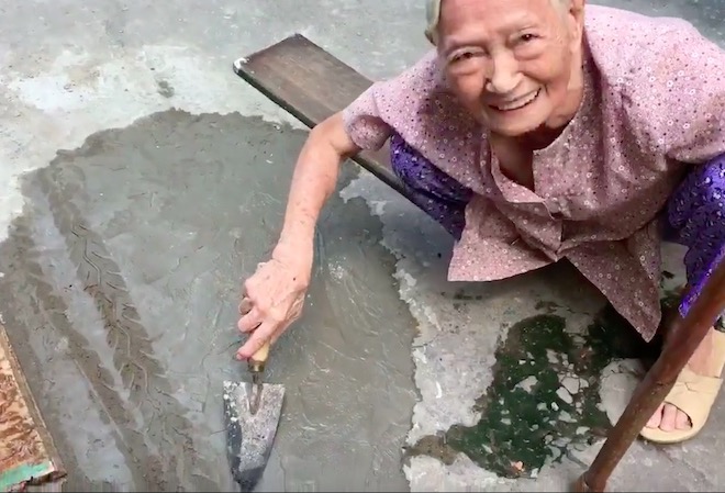 Xôn xao clip cụ bà ngoài 80 tuổi tự trộn xi-măng “vá” đường ở TP.HCM - 1