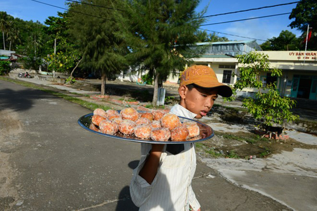 Một cậu bé đi bán bánh rán rong.
