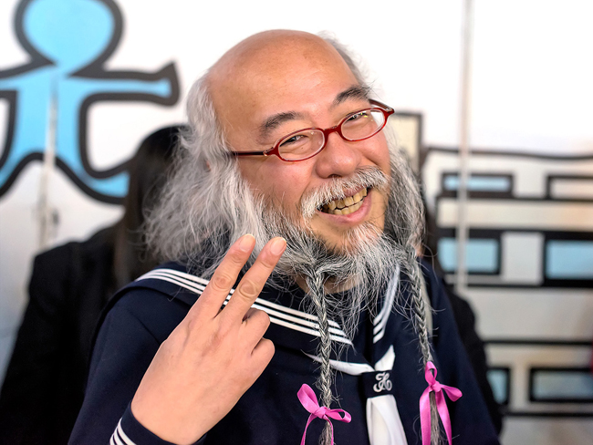 Hideaki Kobayashi là một người đàn ông trung niên với cái đầu hói và bộ râu rậm.  
