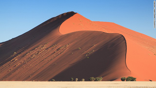 

1. Cồn cát Sossusvlei ở Namibia

Được coi là một trong những thiên đường thiên nhiên ngoạn mục nhất thế giới, không khó hiểu khi Sossusvlei trở thành điểm thu hút khách du lịch nhất của Namibia. Những cồn cát được hình thành từ hàng triệu năm trước từ những bụi cát bay từ dòng sông Orange tới Atlantic. Gió thổi từ hàng triệu năm qua đã 'điêu khắc' Namibia thành những cồn cát cao nhất thế giới. Cát ở đây có màu đỏ của sắt oxit, tuy trông khô cằn nhưng nó vẫn giữ đủ độ ẩm cần thiết cho thực vật sinh sống.
