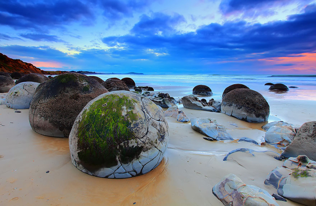 14. Bãi biển Koekohe, New Zealand: Trên bãi biển Koekohe có rất nhiều tảng đá hình tròn lạ kỳ, trông giống như&nbsp;trứng khủng long.&nbsp;Đây thực chất là những&nbsp;khối đá trầm tích, theo thời gian nó đã được làm nhẵn bởi sóng biển.&nbsp;
