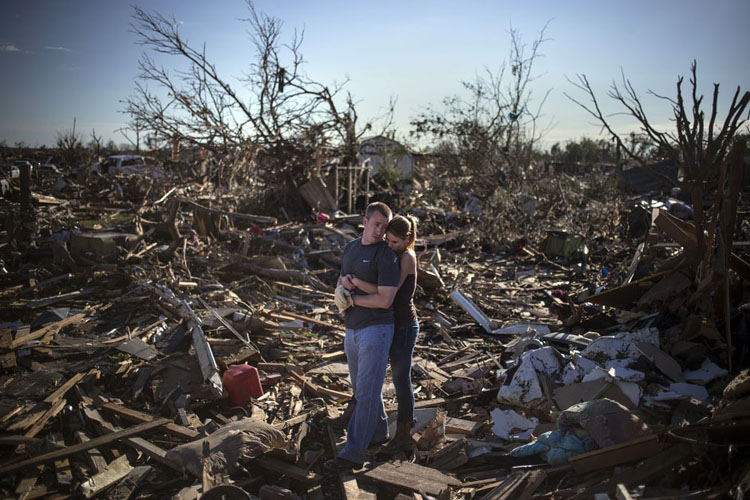 Một cặp đôi dừng lại bên đống đổ nát của căn nhà cũ bị san phẳng sau cơn lốc xoáy hoành hoành ở thị trấn Moore, bang Oklahoma, Mỹ hôm 21/5/2013.
