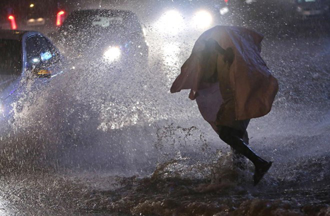 Một người đàn ông mặc áo mưa chạy trốn cơn mưa bất chợt ở Hyderabad, Ấn Độ, ngày 12/11. Ảnh: AP.

