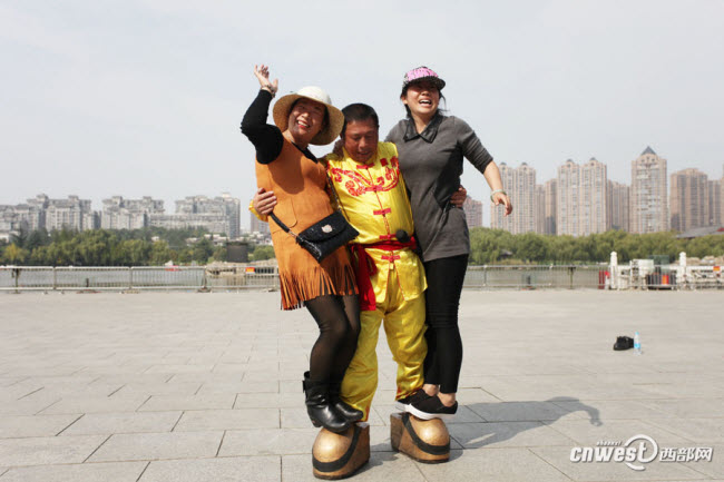Zhang Zhenghui, có biệt danh là “Vua giày sắt”, đi đôi giày bằng sắt nặng 123 kg bước đi với hai người nữ đứng trên giày.