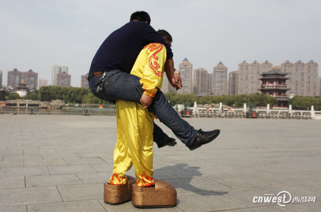 Zhang Zhenghui di chuyển với đôi giày nặng 123 kg và cõng theo một người đàn ông to béo.