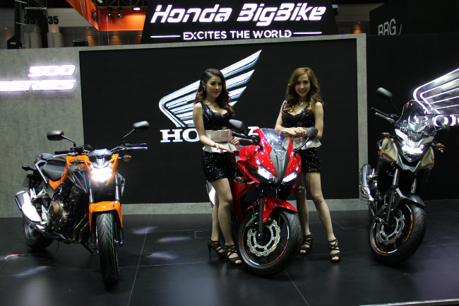 Bộ đôi chân dài đứng trong gian hàng xe mô tô của Honda tại triển lãm.