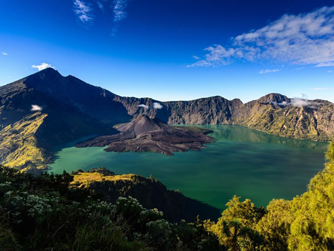 Indonesia với hơn 17.000 hòn đảo lớn nhỏ, thu hút hàng ngàn khách du lịch mỗi năm nhờ những cảnh quan thiên nhiên hùng vĩ đa dạng, khu rừng nhiệt đới tươi tốt và các bãi biển xinh đẹp.

Rinjani (hay Gunung Rinjani) là một trong những ngọn núi lửa cao nhất Indonesia với chiều cao 3.658 mét. Bên cạnh núi Rinjani là một hồ nước hình lưỡi liềm được hình thành trên một miệng núi lửa không còn hoạt động, được xem là một trong những nơi linh thiêng nhất của Indonesia. Mặc cho sự nguy hiểm và độ cao, Rinjani vẫn thu hút rất nhiều khách du lịch, đặc biệt là khách leo núi.
