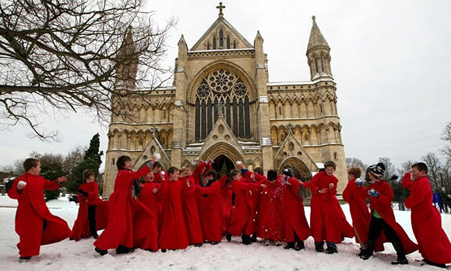 Các thành viên nhí của dàn hợp xướng ở nhà thờ St Albans Cathedral, Anh mặc quần áo đỏ rực chơi ném tuyết.
