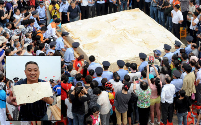 Một người chụp ảnh một chiếc bánh đậu hũ khổng lồ nặng 8 tấn tại thành phố Hoài Nam, Trung Quốc. Hơn 50 công nhân làm việc liên tục trong vòng 7 giờ để hoàn thành chiếc bánh này.