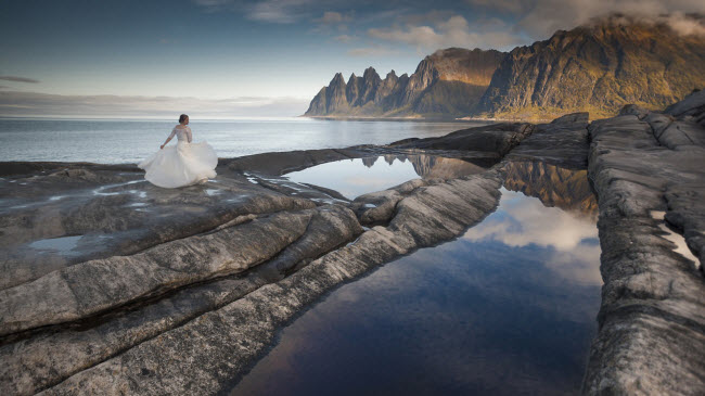 Mặc trang phục váy cưới, cô dâu Nienartowicz nhảy múa trên bãi đá trước biển để hiện niềm vui với cuộc sống mới.