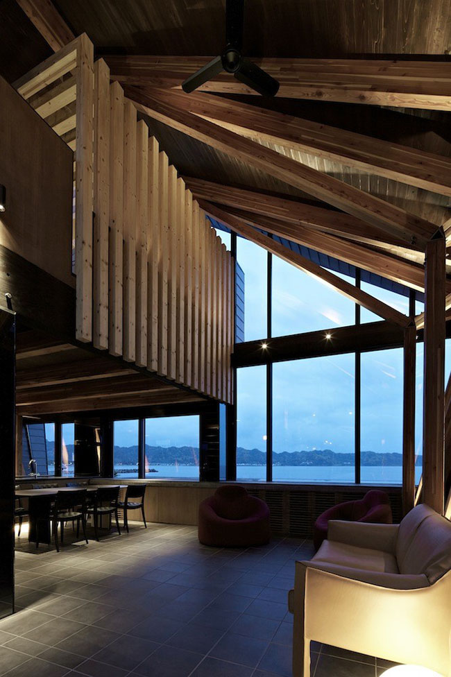Phòng khách đơn giản sáng sủa với khung cửa sổ lớn trông ra biển và những chiếc ghế bọc da theo phong cách hiện đại.