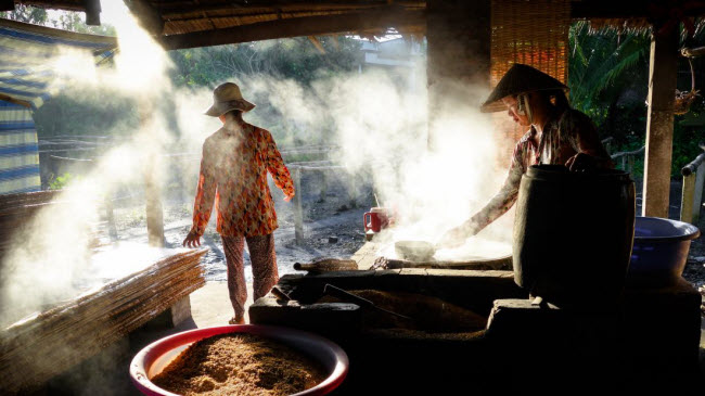 Người dân chuẩn bị hàng hóa để bán tại chợ nổi ở vùng Đồng bằng sông Cửu Long.