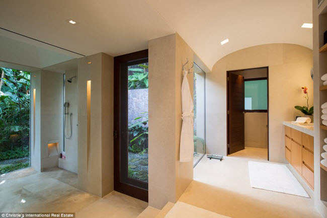 Phòng tắm lớn có sàn lát đá cẩm thạch và tường được lắp nhiều vách kính nhìn ra ngoài.