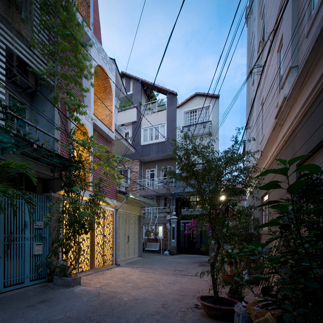 Ngôi nhà nằm trong một ngõ nhỏ ở trung tâm Thành phố Hồ Chí Minh, 3 mặt giáp các ngôi nhà cao tầng khác, mặt tiền là đường bê tông rộng hơn 3m.